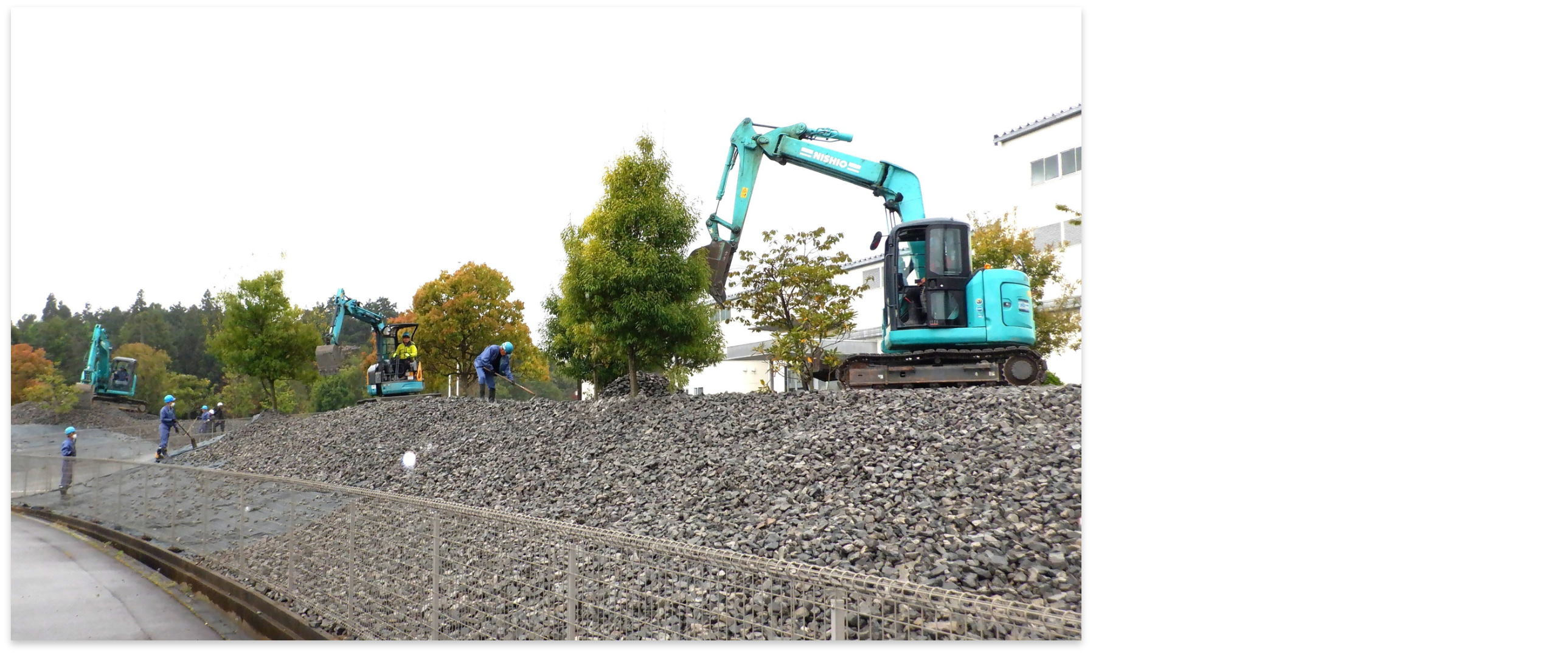 ショベルカーで石を敷き詰める作業員